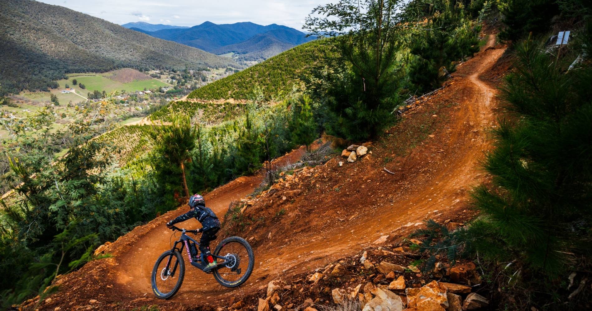 Cyclist decending on single track with bike with landscape mountains in background, Bright Victoria